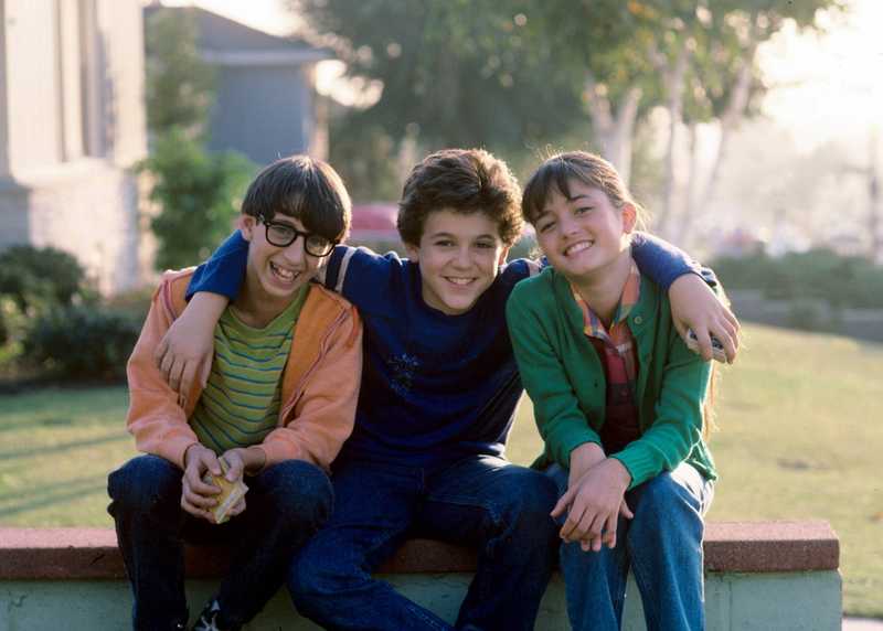 Paul, Kevin e Winnie sentados juntos num muro, sorrindo, em foto de divulgação de Anos Incríveis