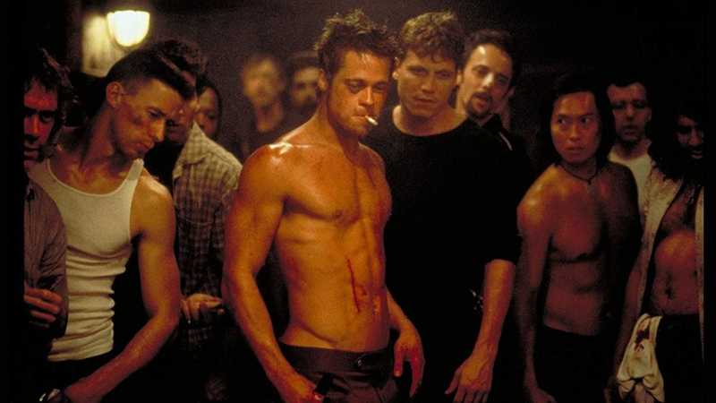 Brad Pitt como Tyler Durden, sem camisa e com sangue no peito, cercado por membros do Clube da Luta