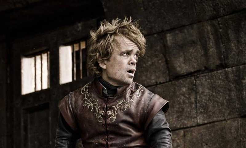 Peter Dinklage como Tyrion Lannister, olhando para o lado diante de uma parede de pedra