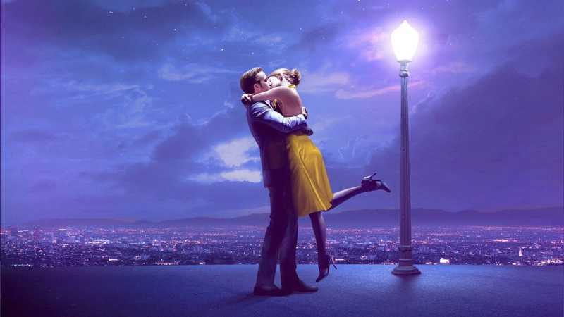 Ryan Gosling e Emma Stone se abraçam e dançam num mirante com vista para Los Angeles ao entardecer em cena de La La Land