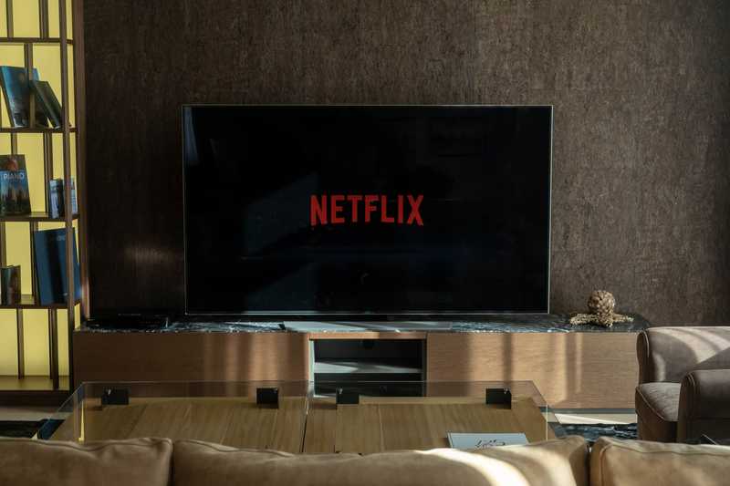 Televisão com o logotipo da Netflix numa sala de estar com sofá e estante de livros
