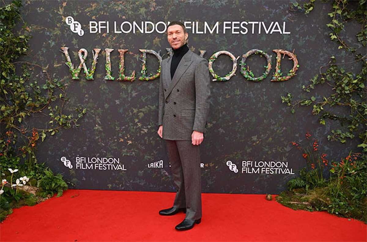 Travis Knight, diretor de O Bosque Selvagem, posa no tapete vermelho do BFI London Film Festival diante do painel com o título Wildwood